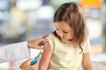 Wall Mural - Doctor vaccinating little girl on hospital background