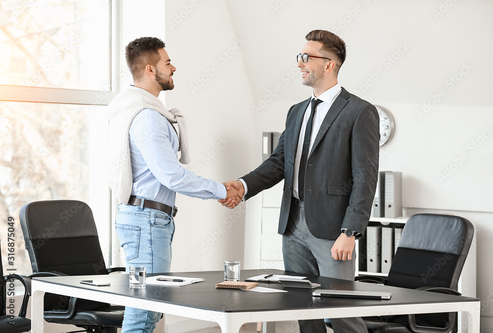 Bank manager and man shaking hands in office