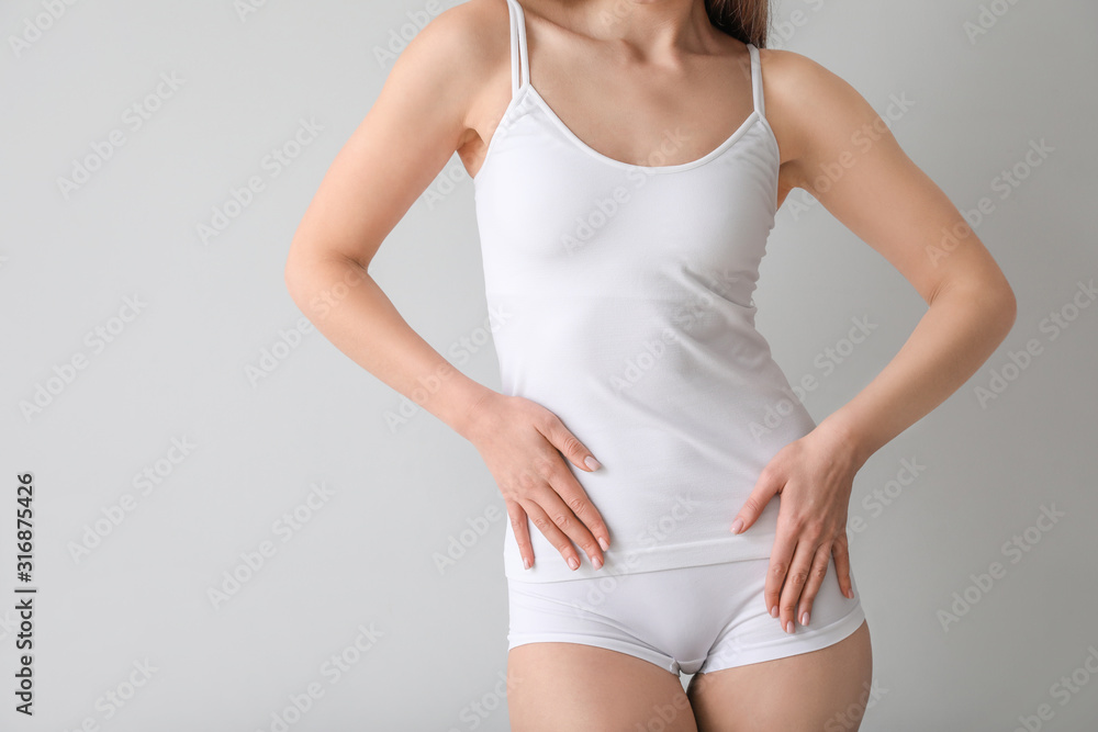 Beautiful young woman in underwear on light background