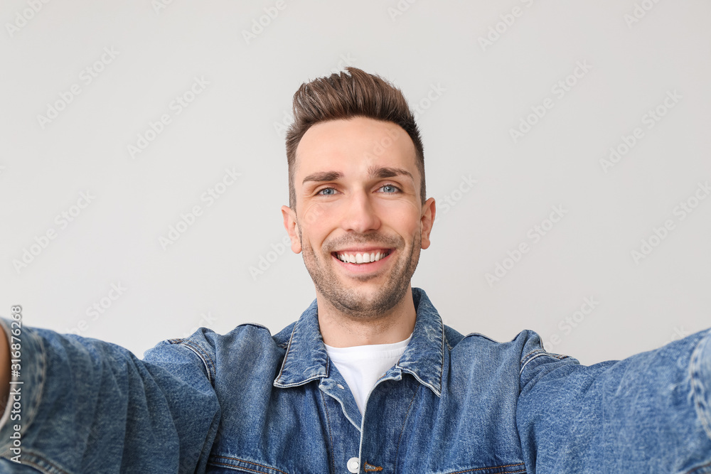 Handsome man taking selfie on light background