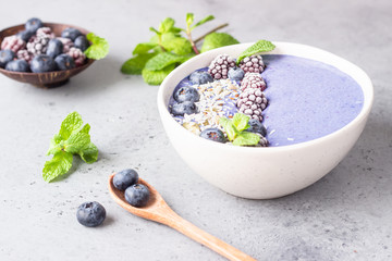 Wall Mural - Violet magic smoothie bowl topped with blueberries, blackberries, coconut flakes and seeds. Healthy breakfast berry smoothie bowl.