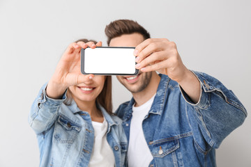 Canvas Print - Young couple taking selfie on light background