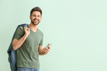 Happy young man with mobile phone on color background