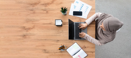 Top view of islamic woman working on laptop at workplace