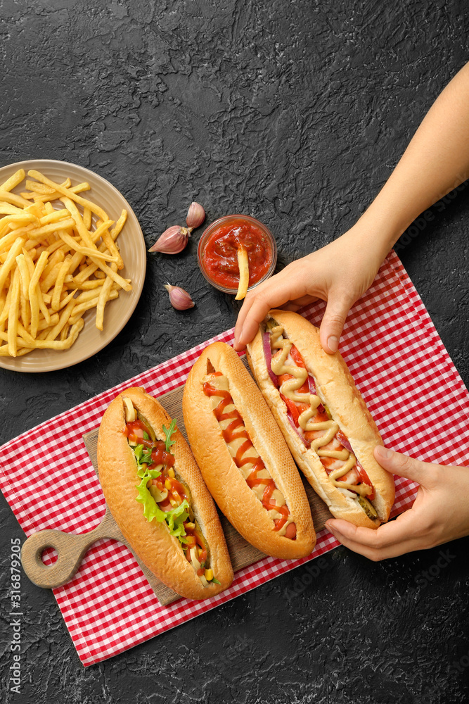 Woman with tasty hot dogs at table