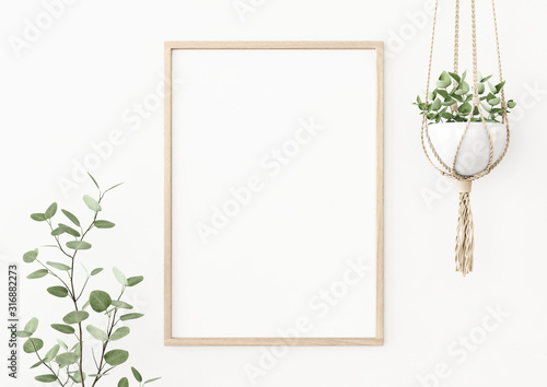 Fotomural Interior poster mockup with vertical wooden frame on empty white wall decorated with plant branch and hanging macrame pot