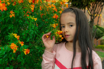 Colombian Latin American girl smells the flowers in the garden of her house