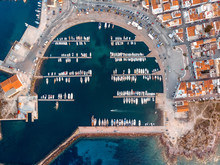 Aerial View Of Semicircular Bay With Moored Boats And Yachts. Reefs And Rocks. Blue Color Of Sea And Orange Tile Rooftops. Drone Photo. Sardinia, Mediterranean Island. Vacation And Tourism Concept.
