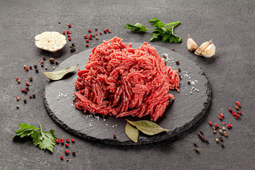 Raw meat products. Veal or mixed homemade minced meat with spices on a black background. board background image, copy space text