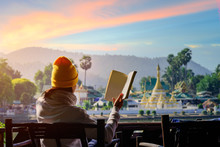 Woman Traveller Relax Sitting On The Terrace Reading Book In The Light Of Morning, Mae Hong Son, Wat Chong Kham The Popular For Tourist Place