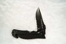 Closeup Of An Open Black Pocket Knife Under The Lights On A White Fabric