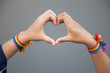 hand of LGBT women holding together, forming heart shape with rainbow ribbon symbol; concept of LGBT pride, LGBTQ people, lgbt rights campaign, same sex marriage
