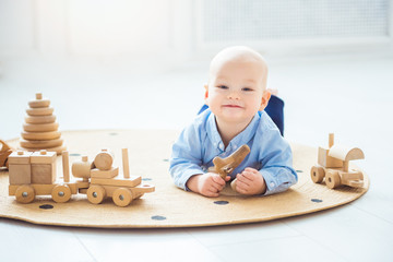 Baby boy playing with wooden toys lying on the Mat. Ecology, education, upbringing concept