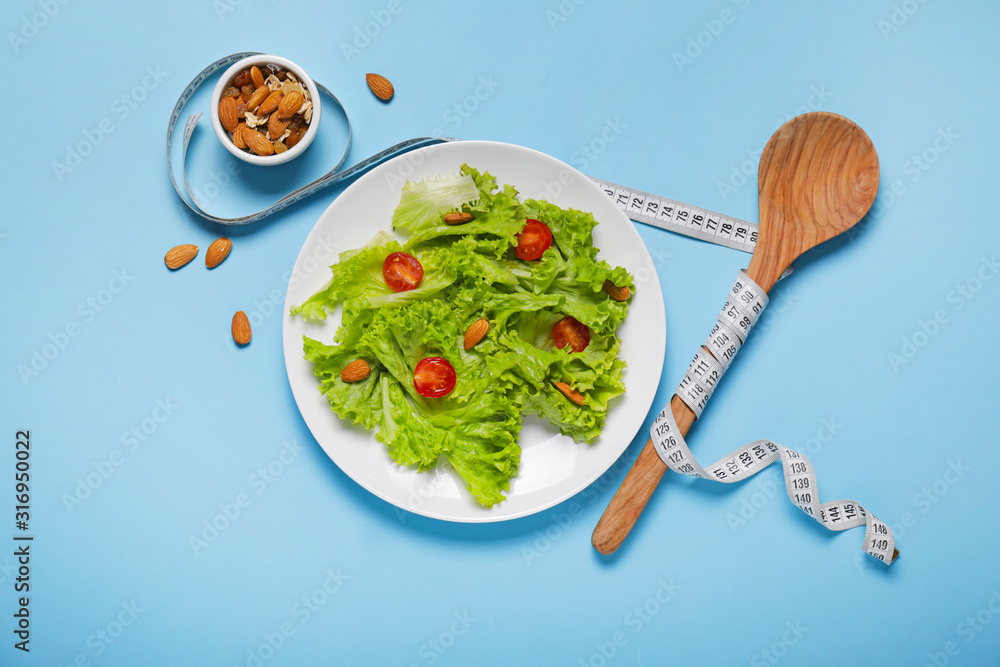 Healthy salad with measuring tape on color background. Diet concept