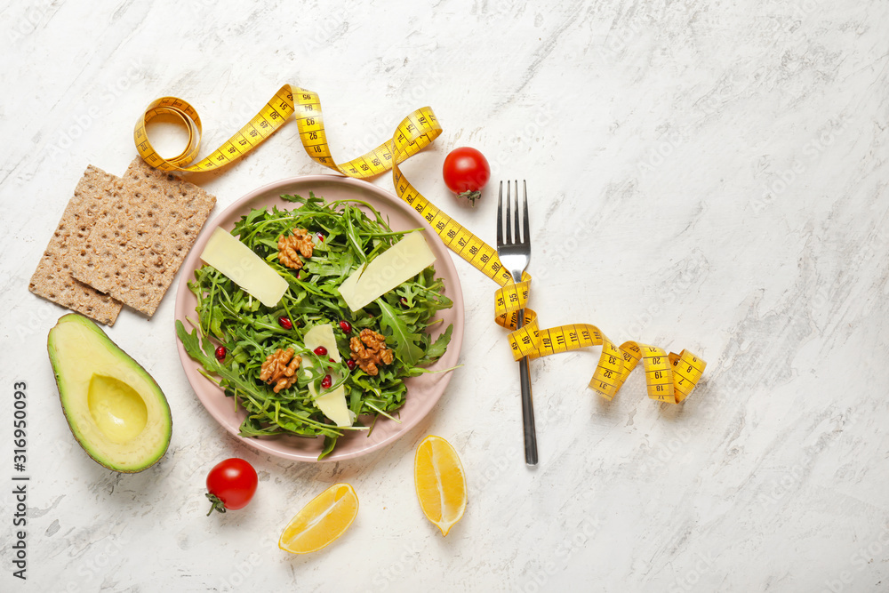 Healthy food with measuring tape on light background. Diet concept
