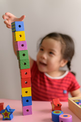 Little curly asian girl enjoy playing with wooden toy blocks isolated on white background. Education and learning Concept.