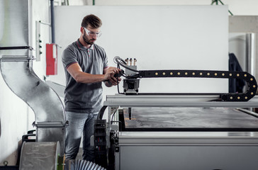 Wall Mural - Young engineer setup plasma cutter for work in metalwork workshop.