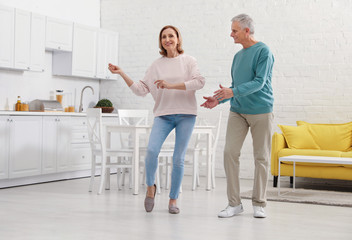 Poster - Happy senior couple dancing together in kitchen