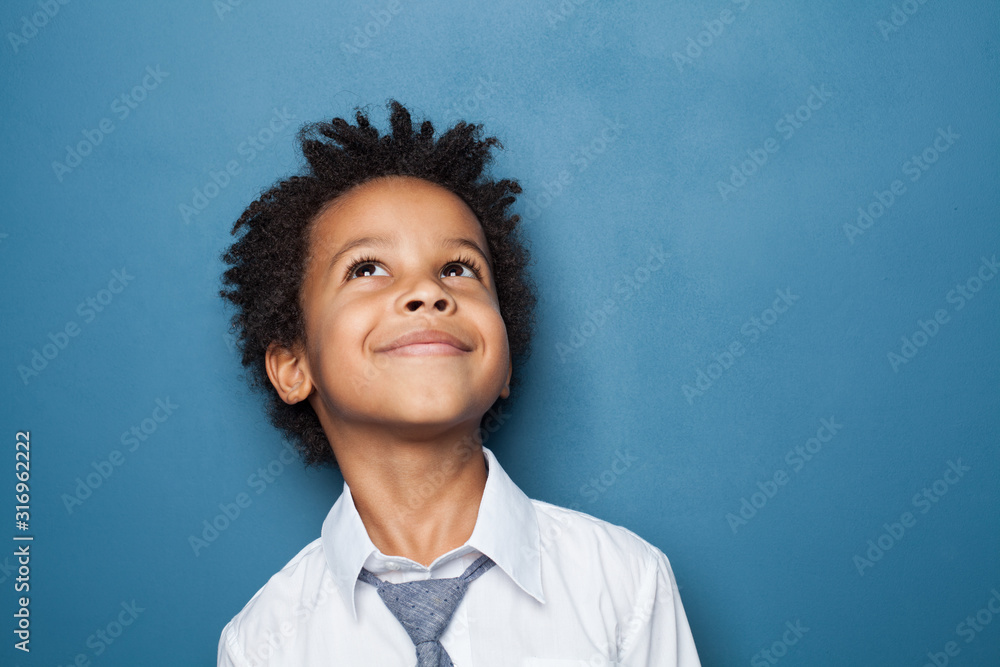 Happy kid school boy portrait. Little child boy looking up on blue background - obrazy, fototapety, plakaty 
