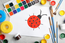 Flat Lay Composition With Child's Painting Of Ladybug On Marble Table