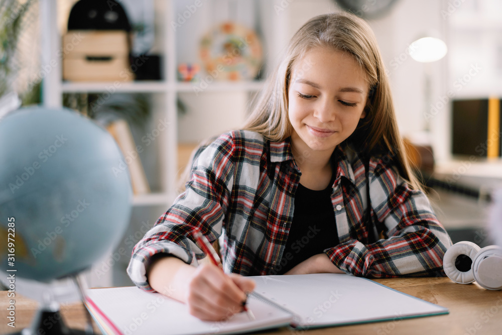 Young girl doing homework. Beautiful little girl at home learning  - obrazy, fototapety, plakaty 