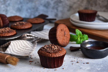 Wall Mural - Chocolate muffins with chocolate moss sauce and mint on a concrete background.