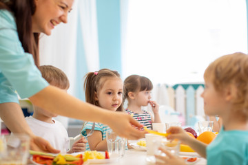 Wall Mural - Group of kindergarten kids have lunch in day care