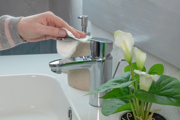 Female hands clean the sink in the bathroom. Dry the white sink. Side view, close up.