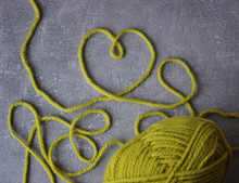 Light Green Heart Of Threads And A Ball Of Thread On A Gray Concrete 