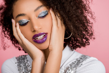 Wall Mural - tender african american woman with silver glitter eyeshadows and purple lips wearing paillettes dress, isolated on pink