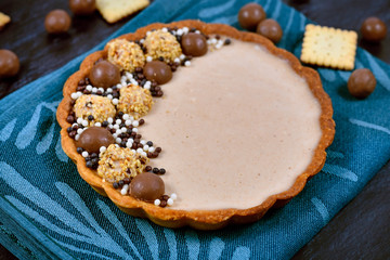 Wall Mural - Sweet tart with cheesecake milk chocolate cream filling topped with pralines and chocolate sprinkles