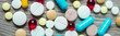 Banner of A lot of colorful medication and pills from above on grey wooden background.