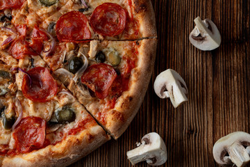 Close up of hot and spicy pizza with jalapeno, pepperoni and red onion on dark wooden background