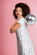© LIGHTFIELD STUDIOS - stylish african american girl in paillettes dress holding disco ball, isolated on pink