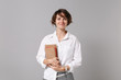 © ViDi Studio - Smiling beautiful young business woman in white shirt posing isolated on grey wall background studio portrait. Achievement career wealth business concept. Mock up copy space. Holding books, notebooks.