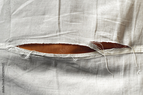 Fotografía Unbleached beige fabric with torn stitch, hole and loose threads