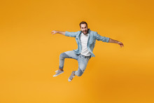 Cheerful Young Bearded Man In Casual Blue Shirt Posing Isolated On Yellow Orange Background, Studio Portrait. People Sincere Emotions Lifestyle Concept. Mock Up Copy Space. Jumping Spreading Hands.