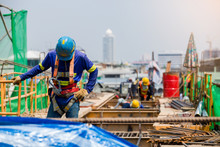 Builder Worker In Safety Protective Equipment. Professional Industrial Climber In Helmet And Uniform Works At Height. Risky Extreme Job. Industrial Climbing At Construction Site.