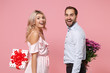 © ViDi Studio - Excited couple two guy girl in party outfit celebrating isolated on pink background. Valentine's Day Women's Day birthday holiday concept. Hold present box with gift ribbon bow, bouquet of flowers.