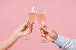 © ViDi Studio - Close up cropped photo of female, male hold in hands glass of champagne isolated on pastel pink background. Copy space advertising mock up. Valentine's Day Women's Day birthday holiday party concept.