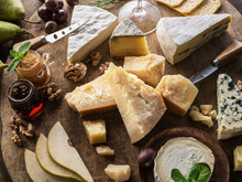 Cheese Platter With Organic Cheeses, Fruits, Nuts And Wine On Wooden Background. Top View. Tasty Cheese Starter.