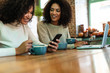 © Drobot Dean - Two cheerful young african girlfriends sitting at the cafe