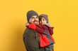 Happy father and son in warm clothes on yellow background. Winter vacation