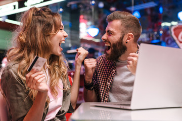 Wall Mural - Loving couple using laptop computer holding credit card.