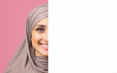 Poster - Smiling arabic woman in hijab standing behind white advertisement board