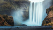 Alone tourist overlooking waterfall at Skogafoss, Iceland