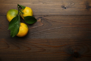 branch with yellow tangerines on a wooden background with copy space