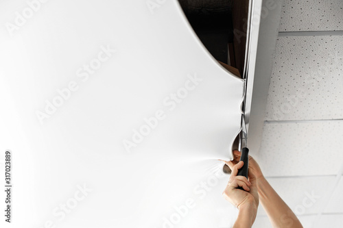 Fotografía Repairman installing white stretch ceiling in room, closeup