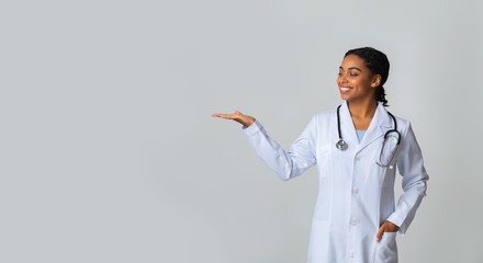 Wall Mural - Afro Female Doctor Holding And Looking At Some Invisible Object On Her Palm