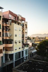 Wall Mural - High angle view of buildings surrounded by greenery with rocks under sunlight on the background